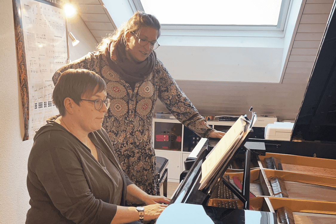 Eine erwachsene Schülerin spielt am Flügel, Valérie Girard begleitet sie