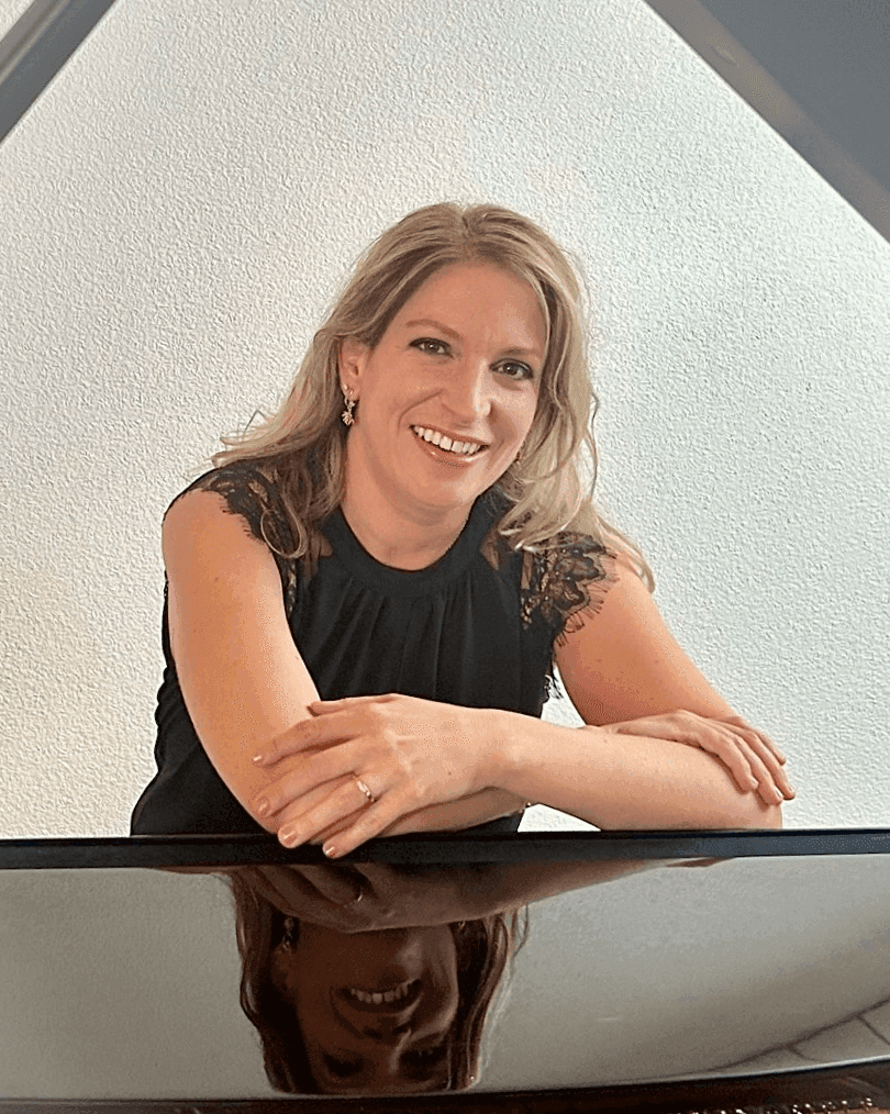 Valérie Girard, Klavierlehrerin, stützt sich lächelnd auf ihren Flügel